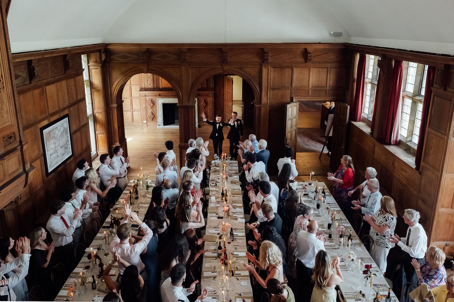Aerial view of guests dining at long tables in an elegant wood-paneled hall during a formal banquet event.