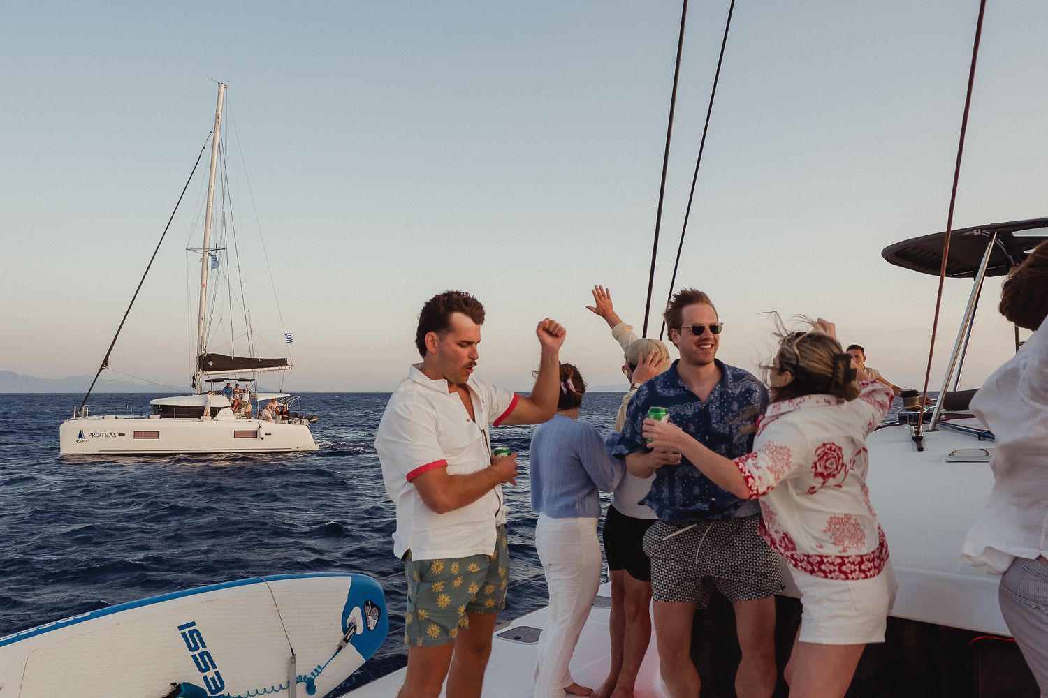 Group of people enjoying a sailing trip on a catamaran yacht in the Mediterranean Sea during sunset.