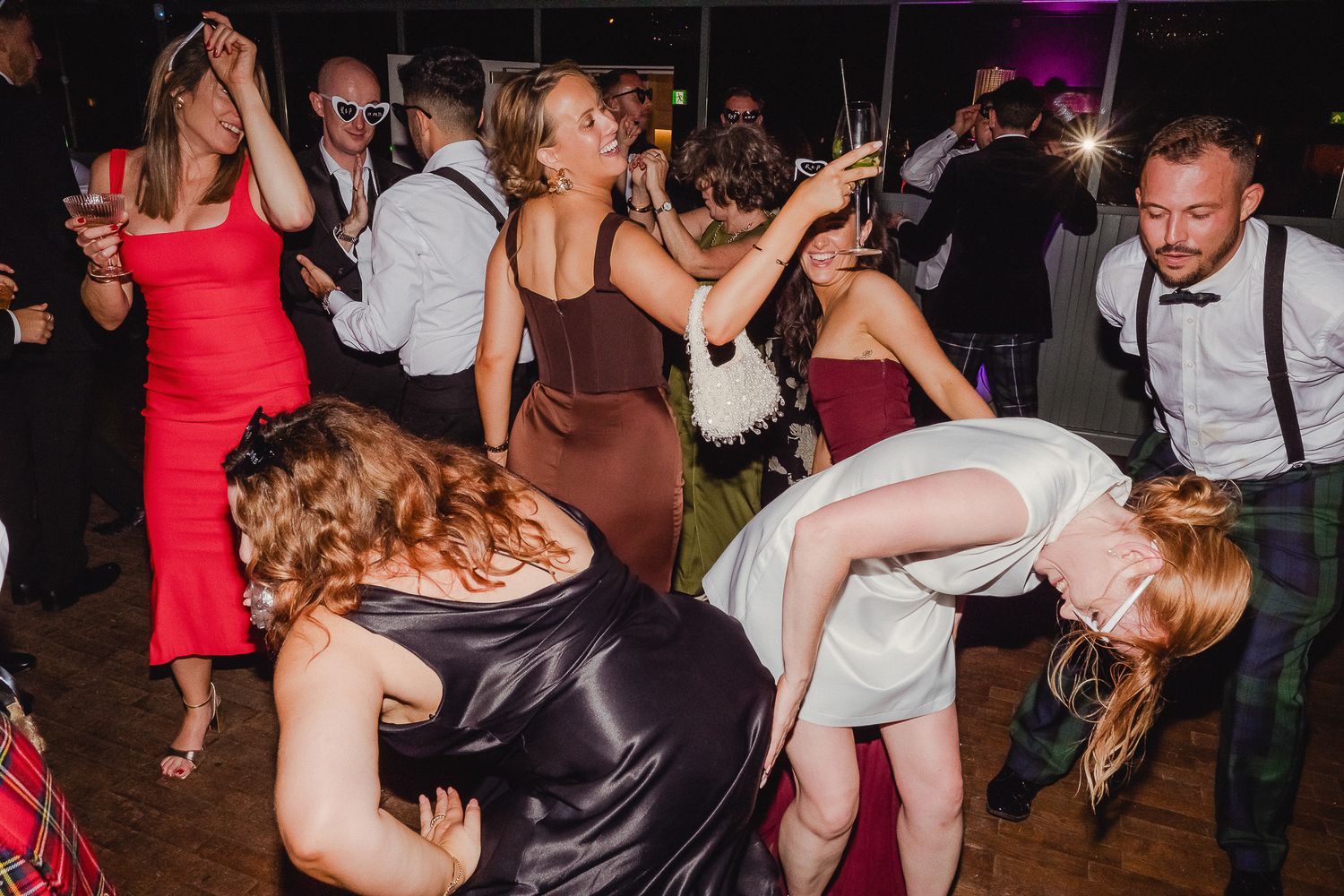 Energetic dancers move to the music at a nighttime celebration with colorful dresses and festive atmosphere.