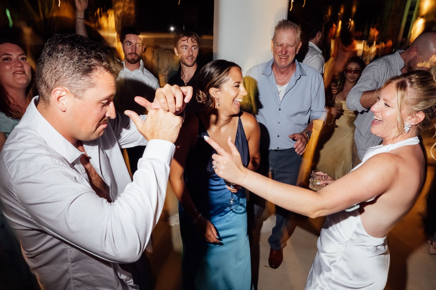 Guests dancing and celebrating joyfully at a lively wedding reception party indoors.
