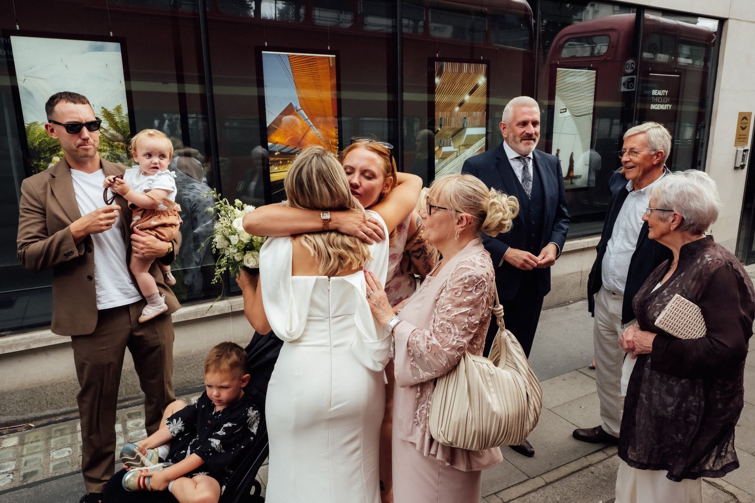 Bride hugging guests outside while family and friends celebrate after wedding ceremony.