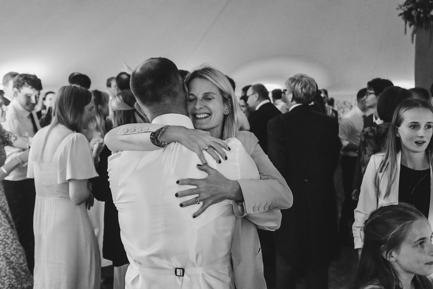 Black and white wedding photos arranged in a filmstrip style showing intimate moments between couples and guests at a celebration.