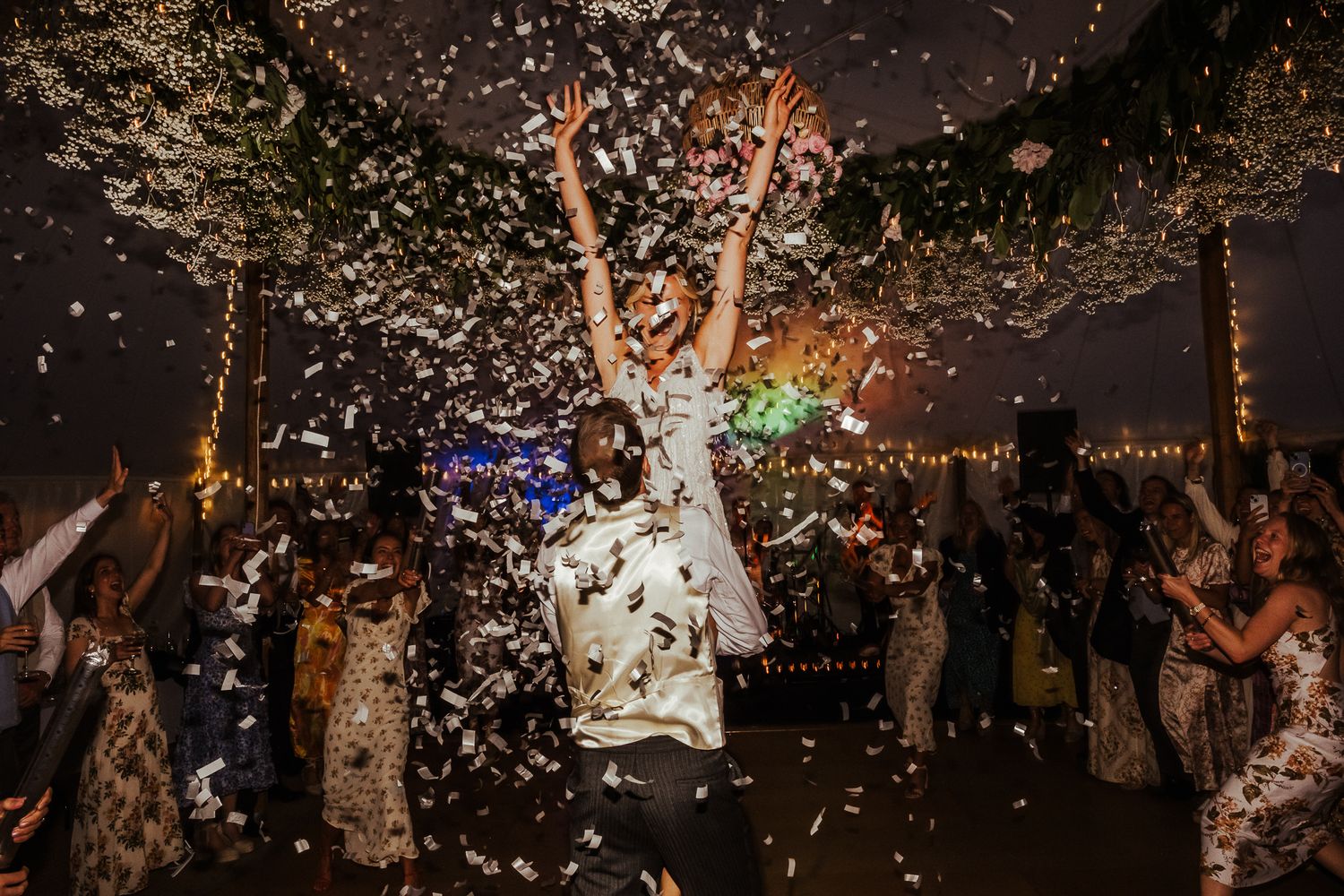Joyful celebration with confetti falling in a dimly lit reception venue.