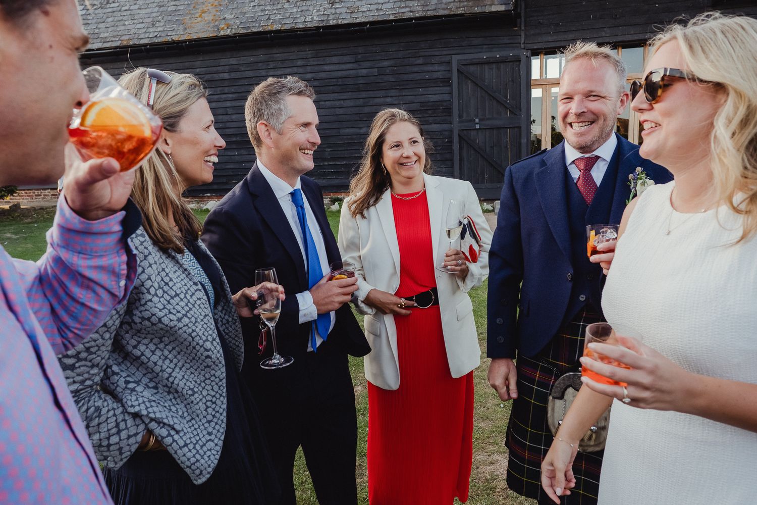 Guests mingle and chat during a wedding reception while holding drinks and enjoying the festivities.