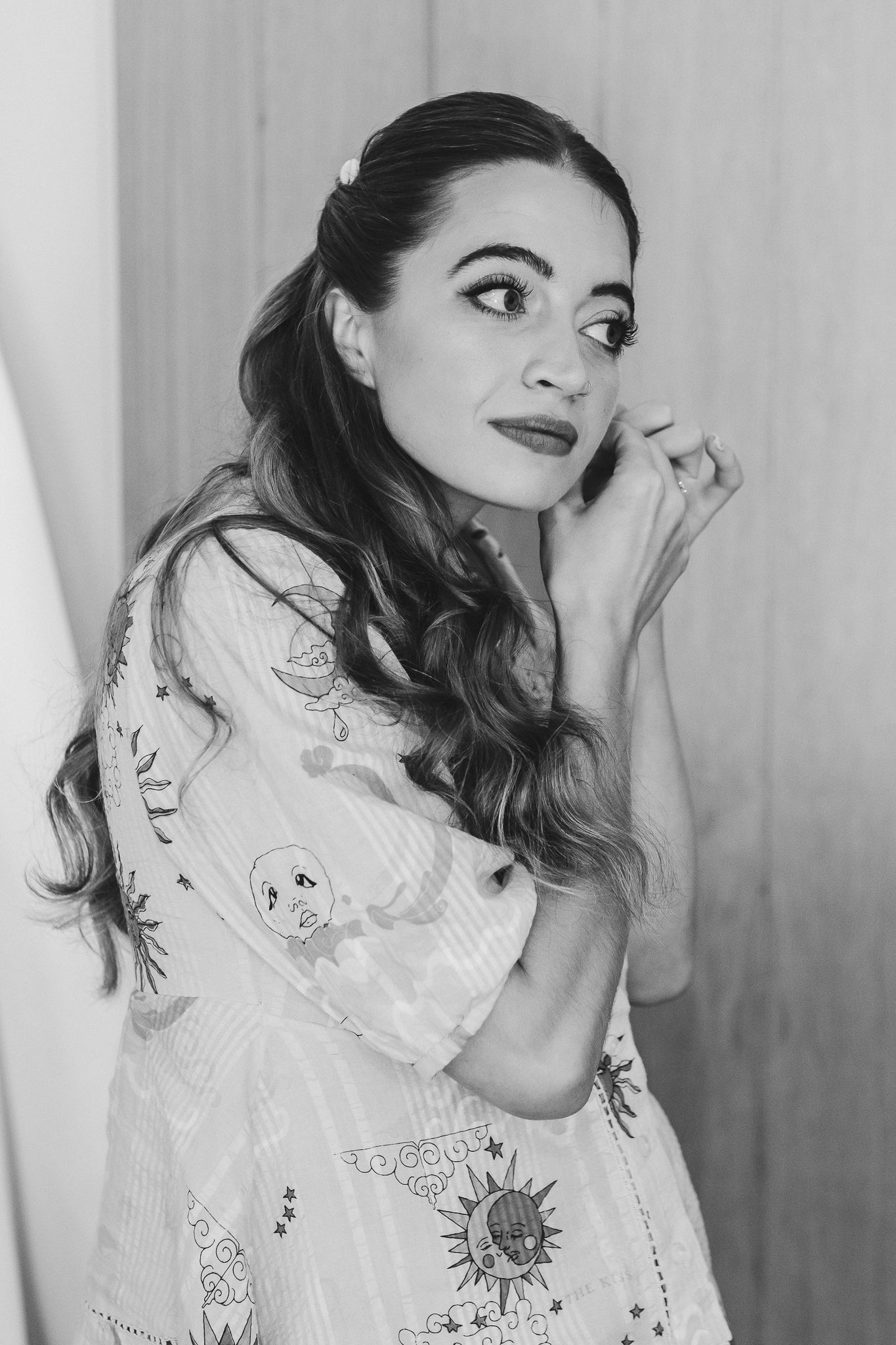 A person in a white lace dress poses playfully in a series of black and white portraits.