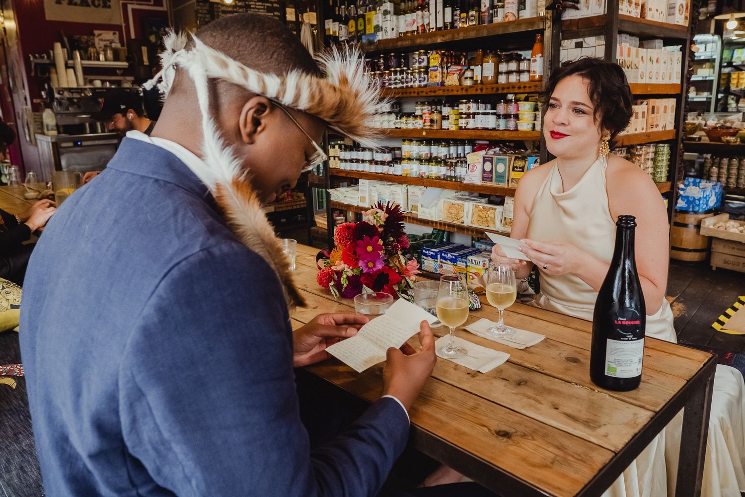 Wine glasses and bottles line a wooden table during an intimate tasting event in a cozy restaurant.