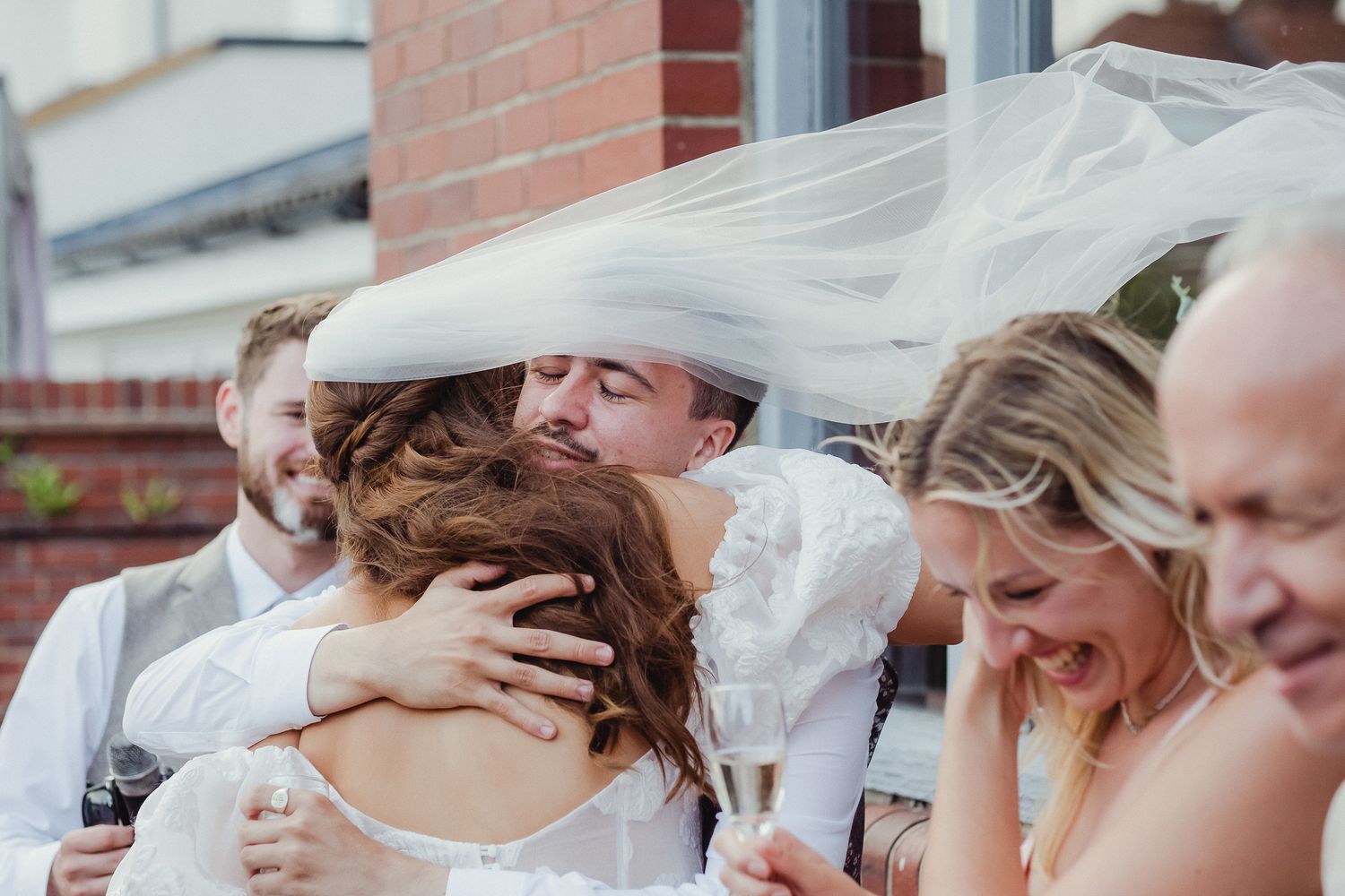 Wedding guests share emotional embraces and joyful moments during an outdoor celebration.