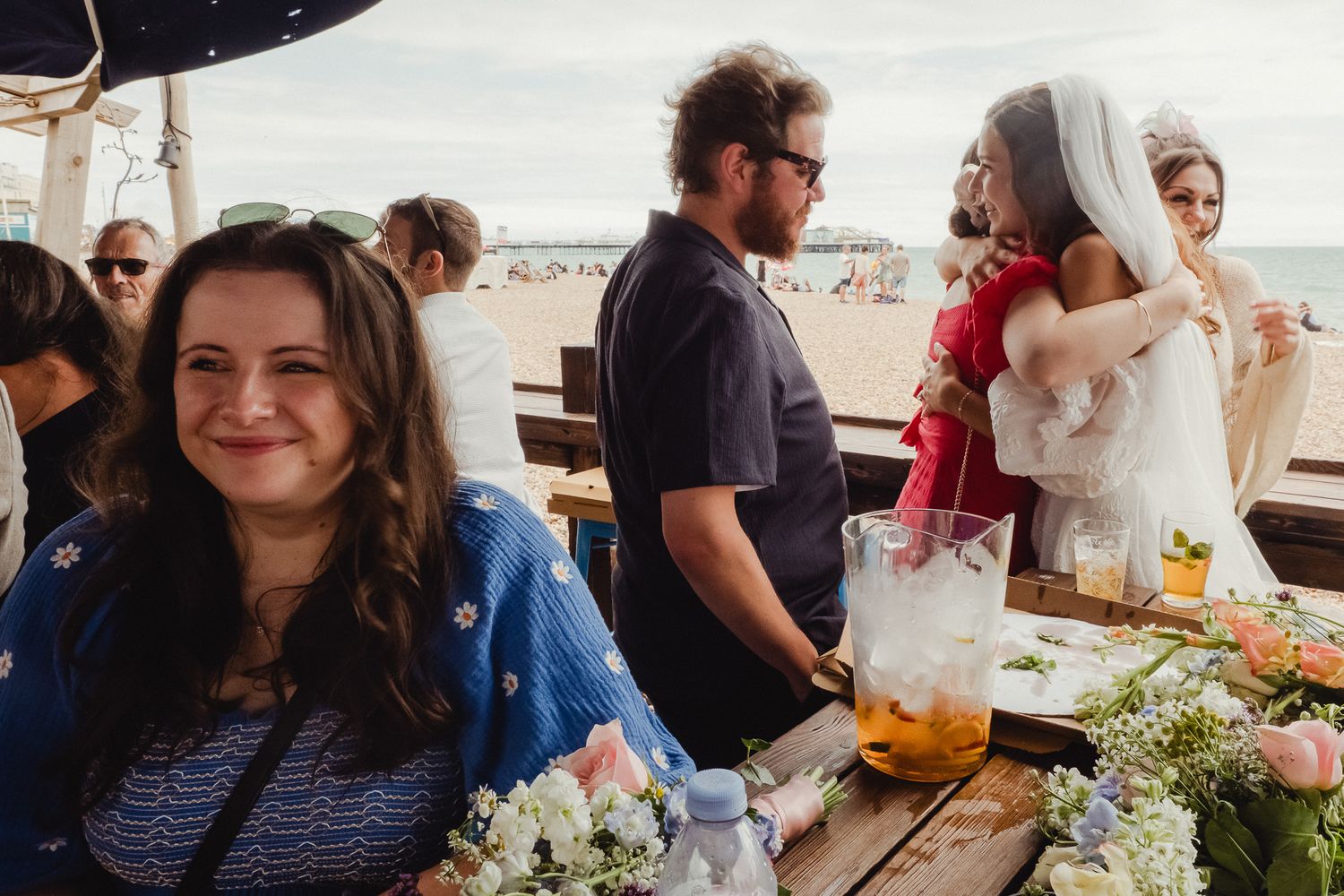 People gathered around a table at a social event with flowers and decorative arrangements.