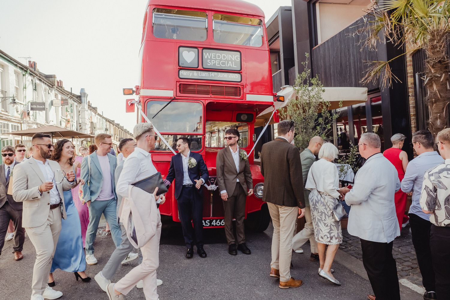A group of people gather around a bright red food truck parked on a sunny street.