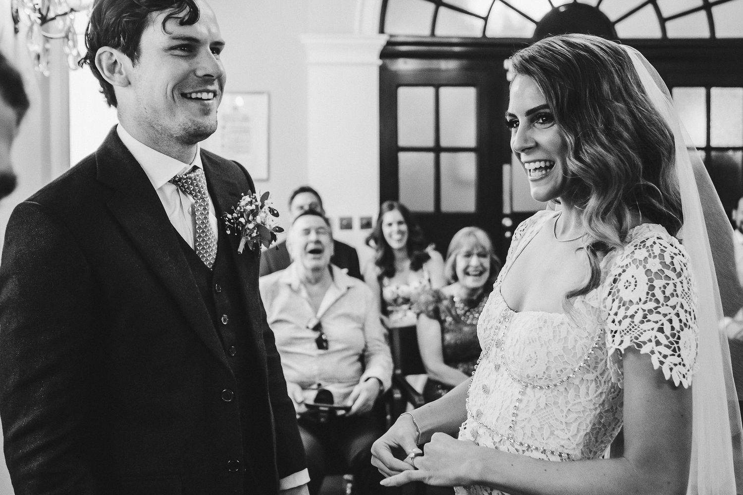 Wedding guests laugh and smile during a joyful celebration at an elegant indoor venue.
