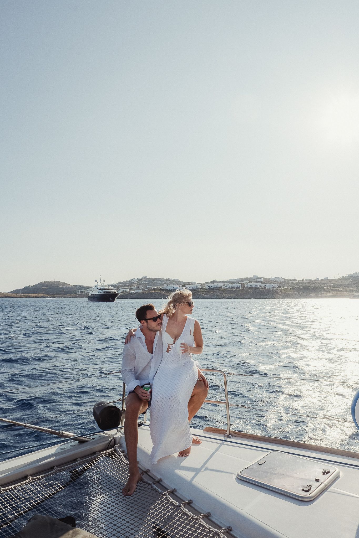 Romantic couple enjoying a sunset yacht cruise along a scenic coastline as they sail across calm blue waters.
