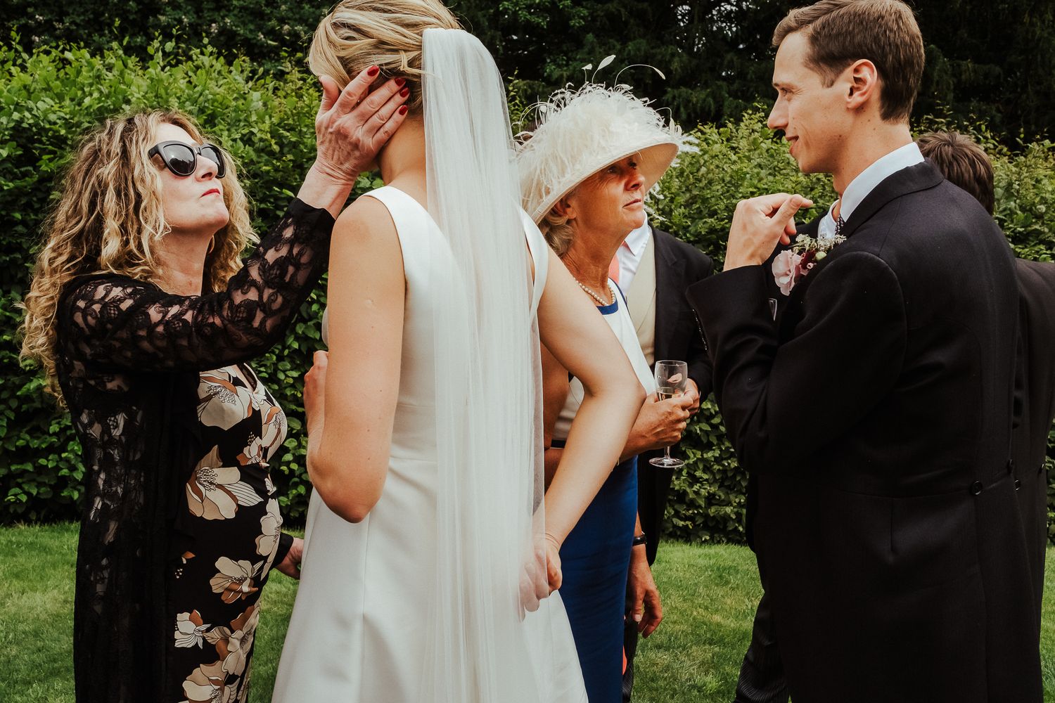 Wedding guests share intimate moments of celebration in a sunny garden setting.