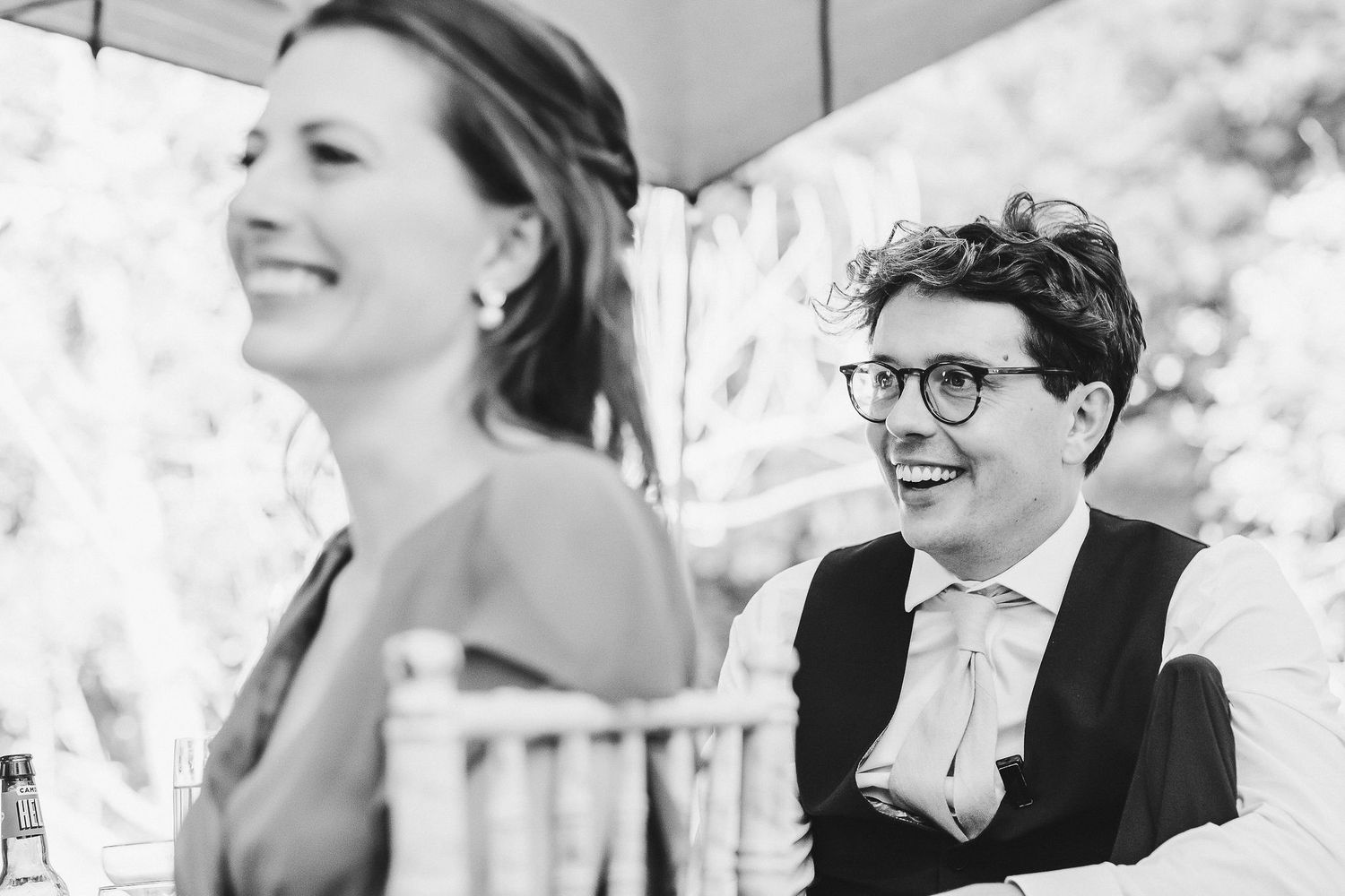 Black and white candid photo of wedding guests enjoying conversation during reception.