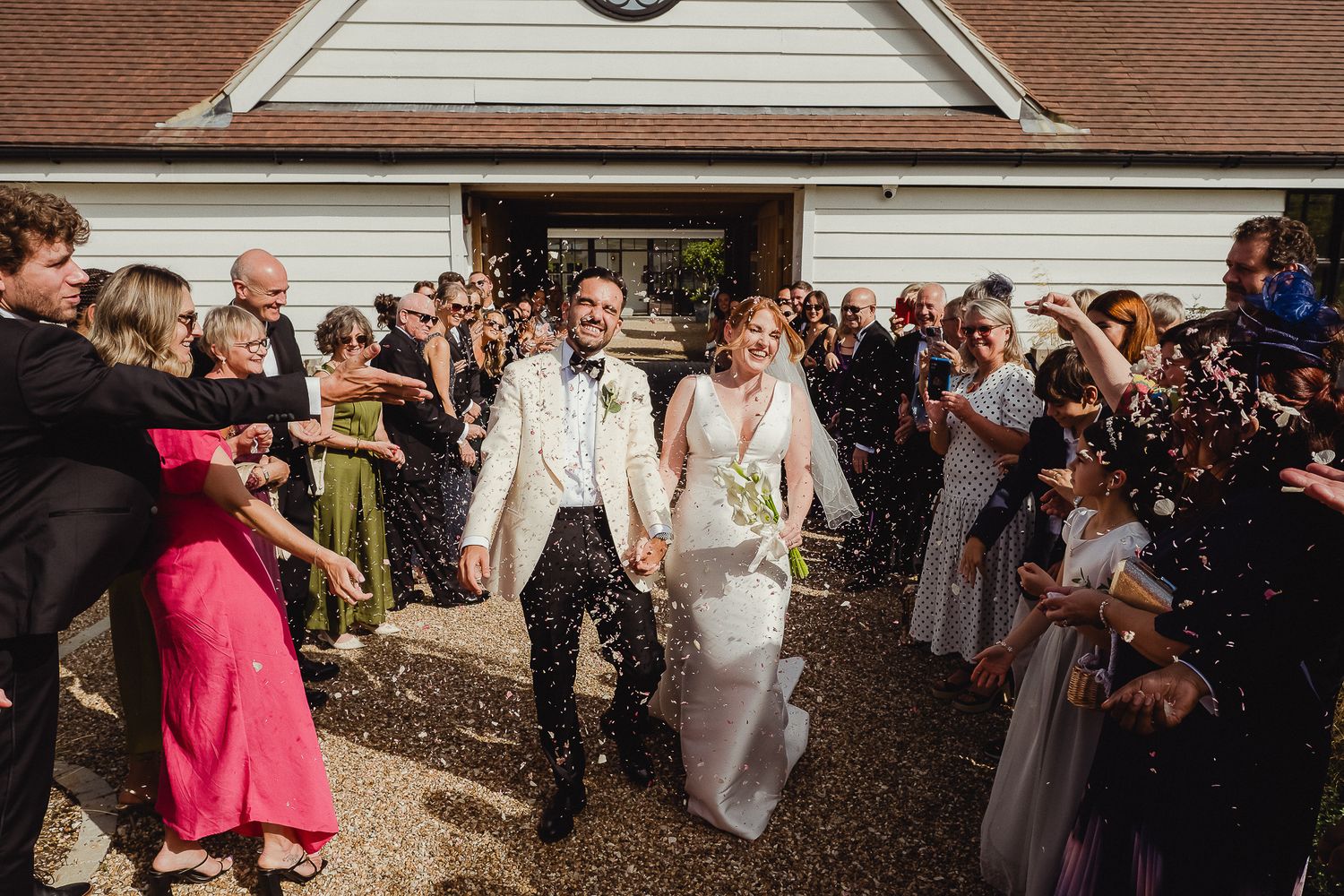 LIMEKILN Wedding Photography - Wedding guests shower the newlyweds with confetti as they exit the ceremony at LIMEKILN in Sussex