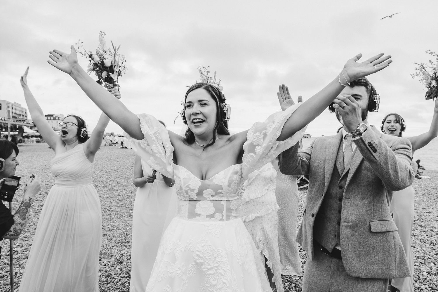 Group of people with raised arms stand joyfully together in a field on a sunny day.