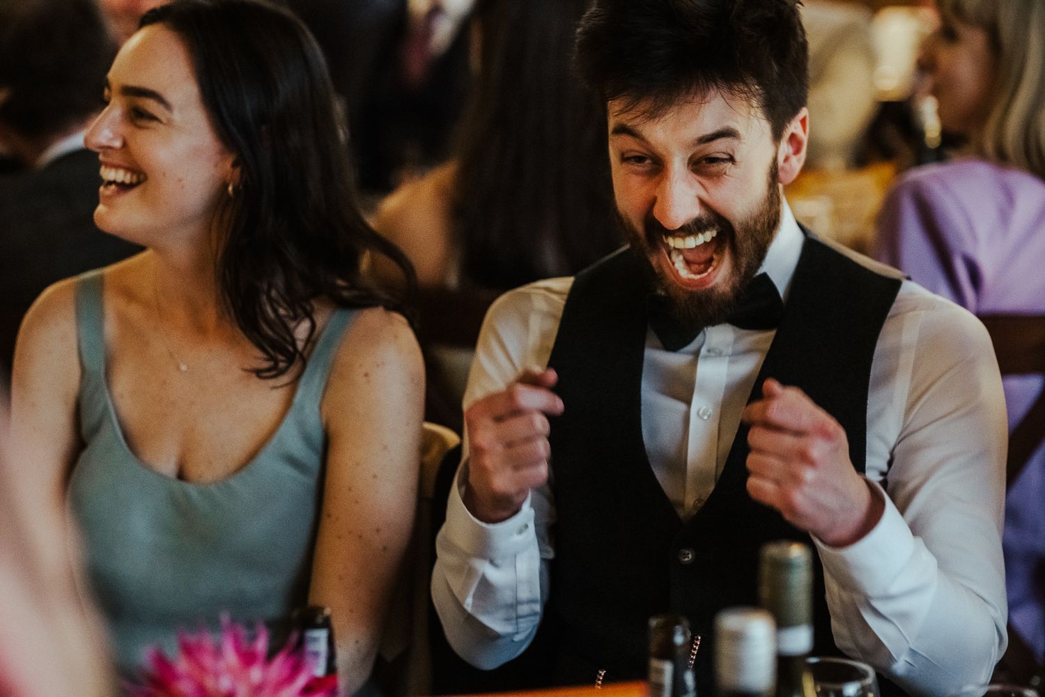 Wedding guests share a joyful moment of laughter during a reception celebration.
