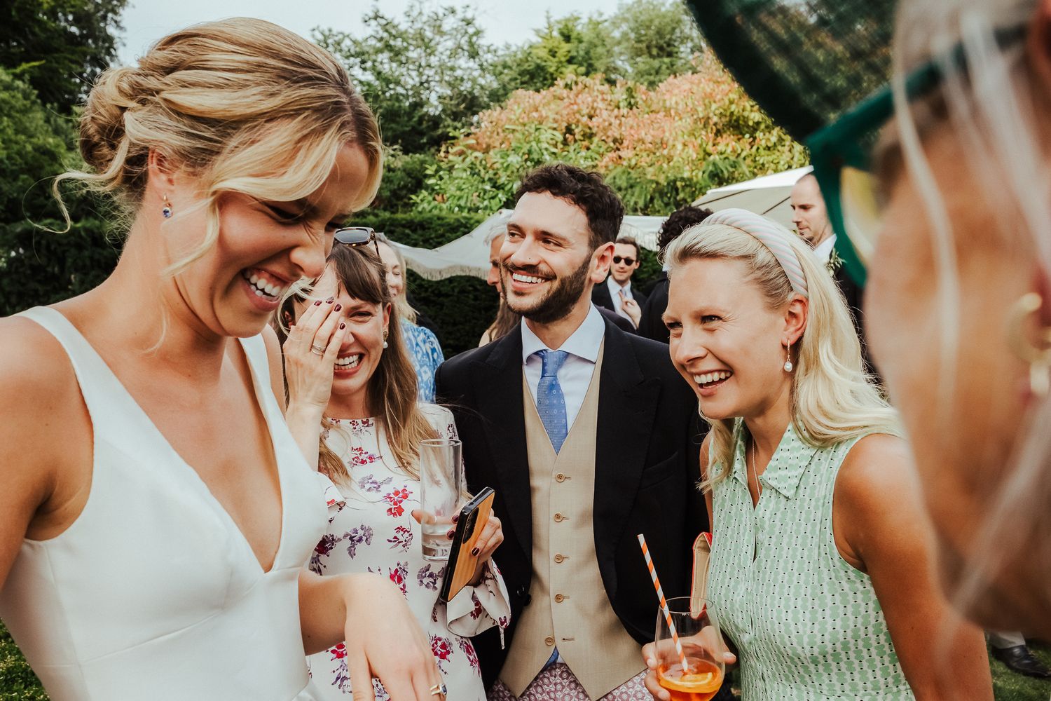 A group sharing genuine laughter during an outdoor wedding celebration.