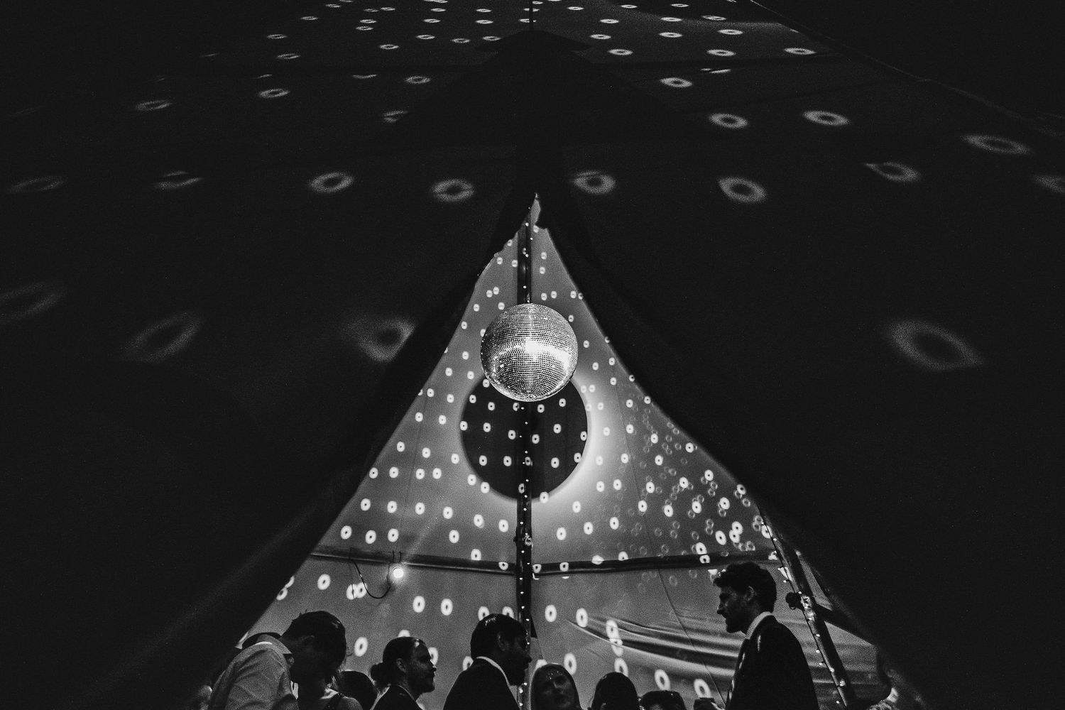 View of a tent ceiling with string lights creating a magical pattern at night.