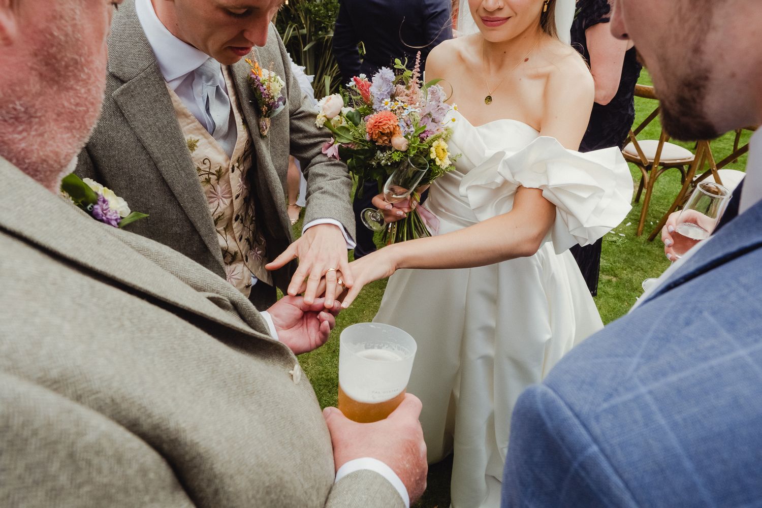 A joyful celebration at an outdoor wedding reception with people mingling and toasting together in a garden setting.
