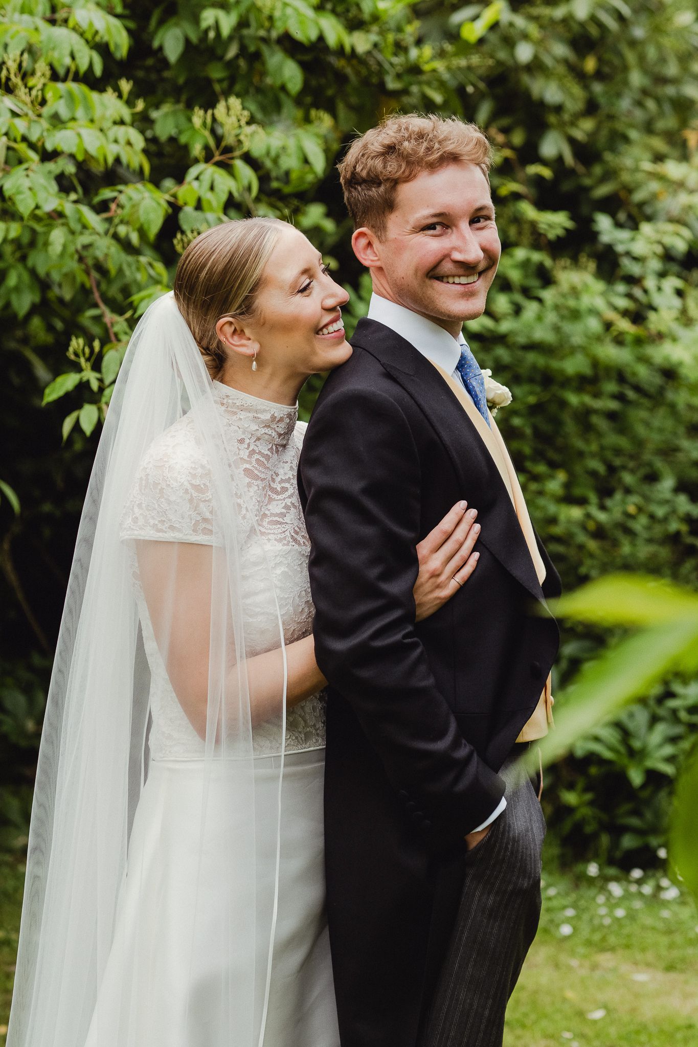 A couple sharing joyful candid moments in a garden setting during their elegant outdoor wedding ceremony.