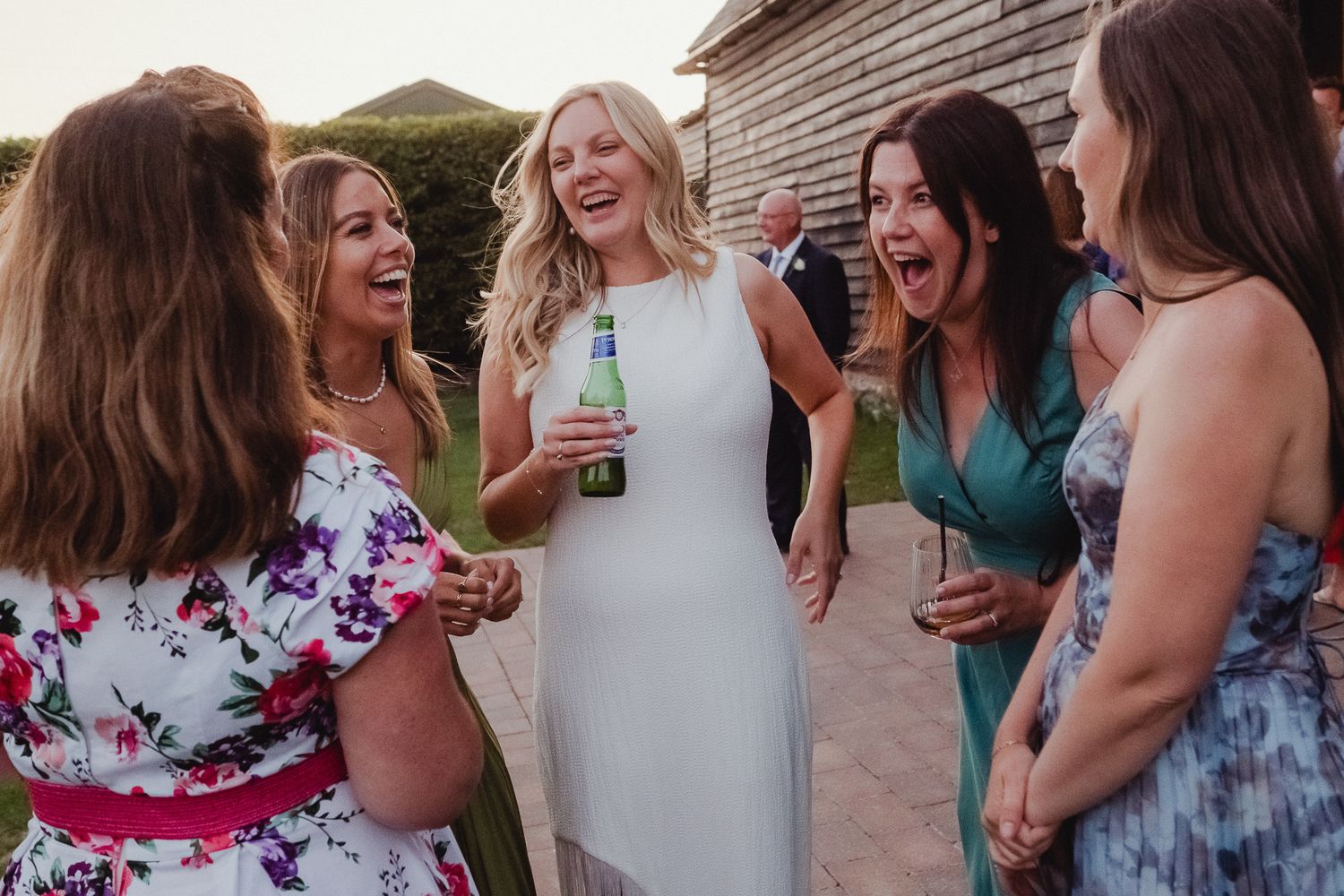 A group of wedding guests laughing and socializing together during an outdoor celebration.