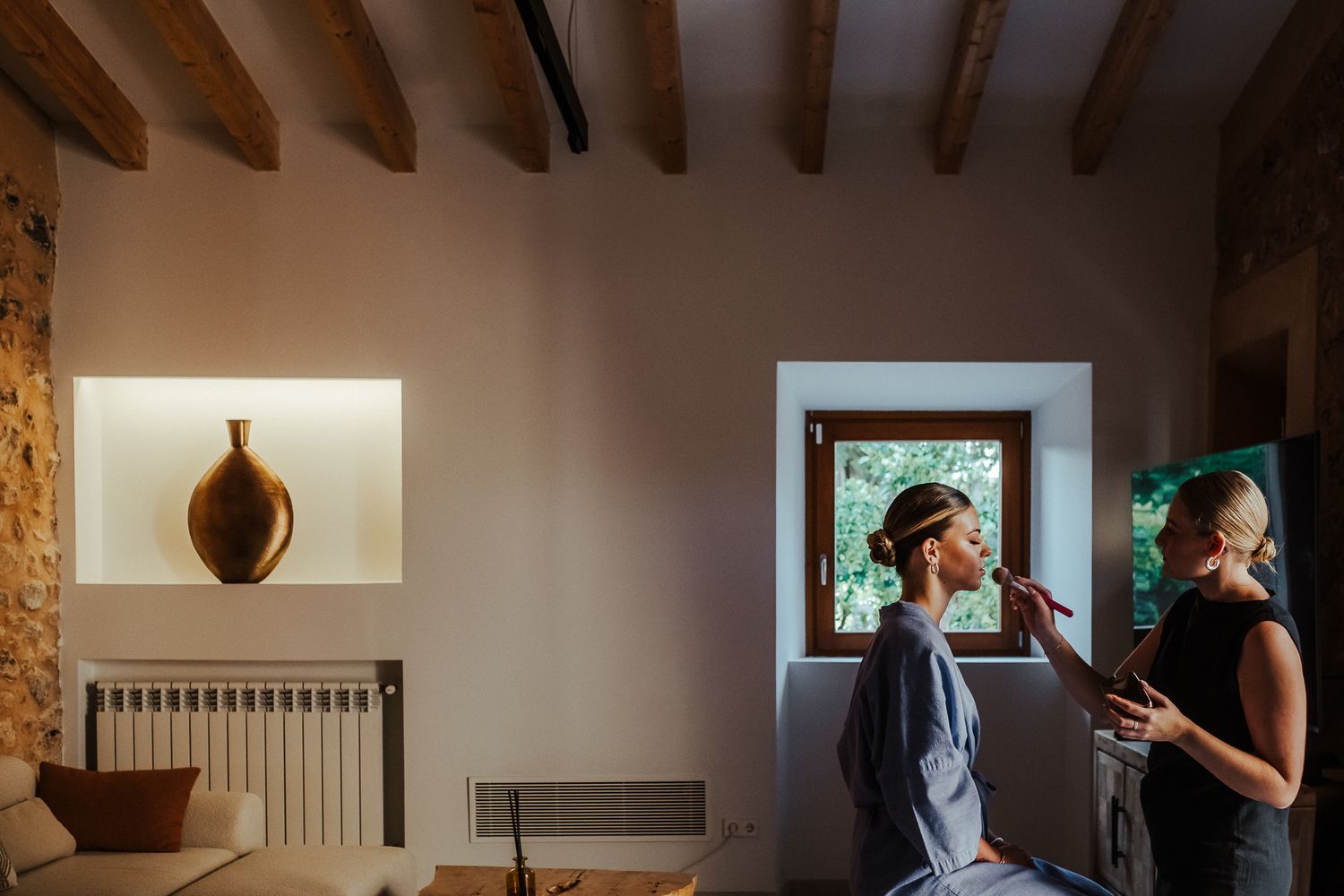 A rustic indoor hallway with wooden beams and multiple framed photographs displayed along a white wall.