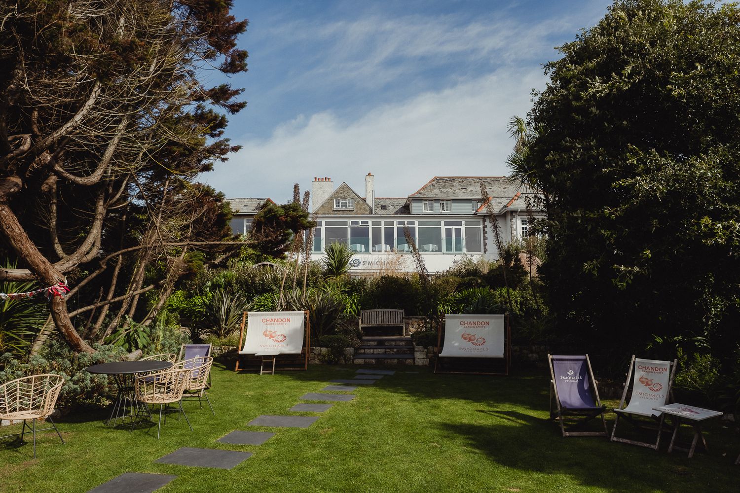 Panoramic view of a coastal property with white houses and lush landscaping overlooking the ocean on a sunny day.
