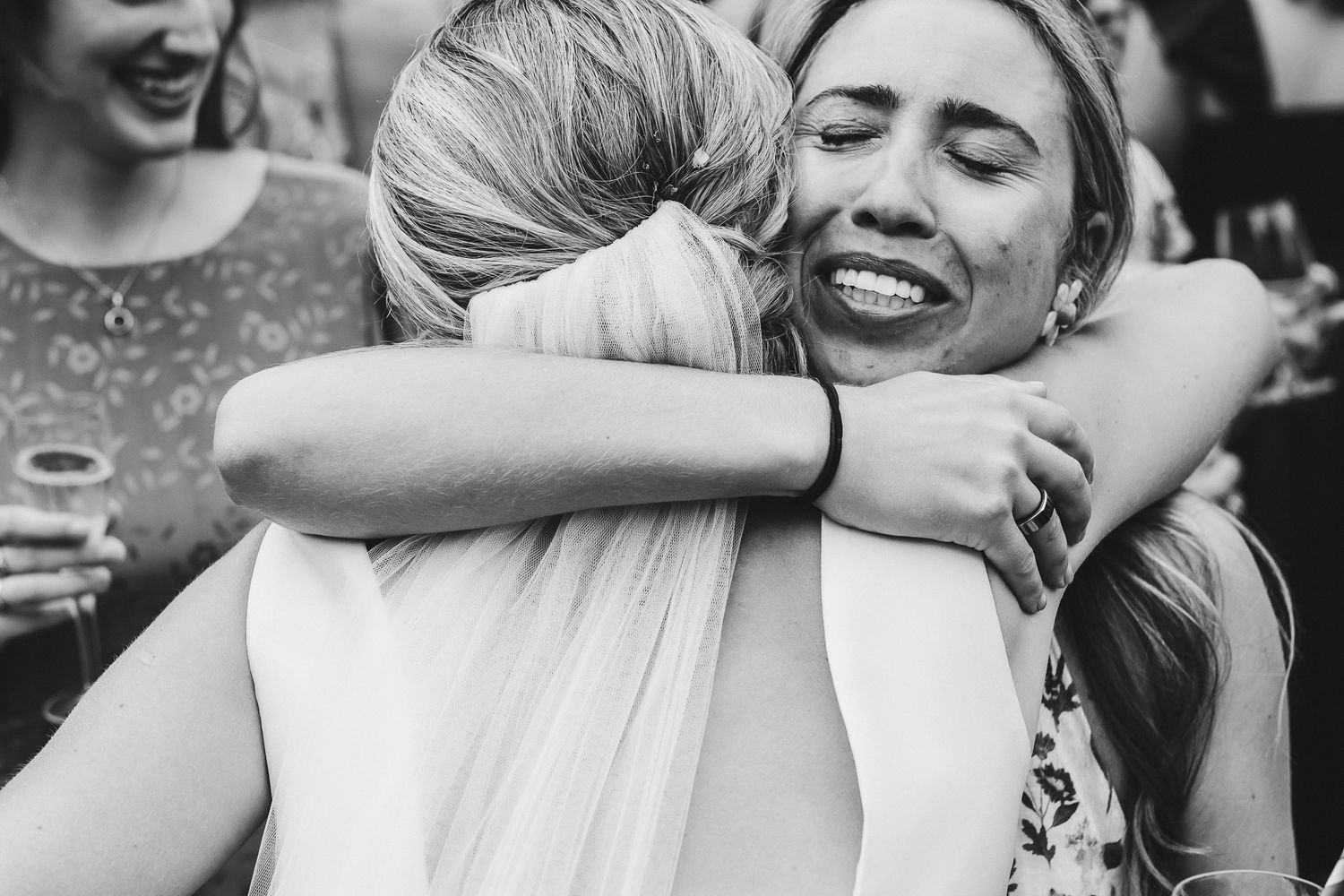 Two people embracing in a joyful black and white moment at a celebration.