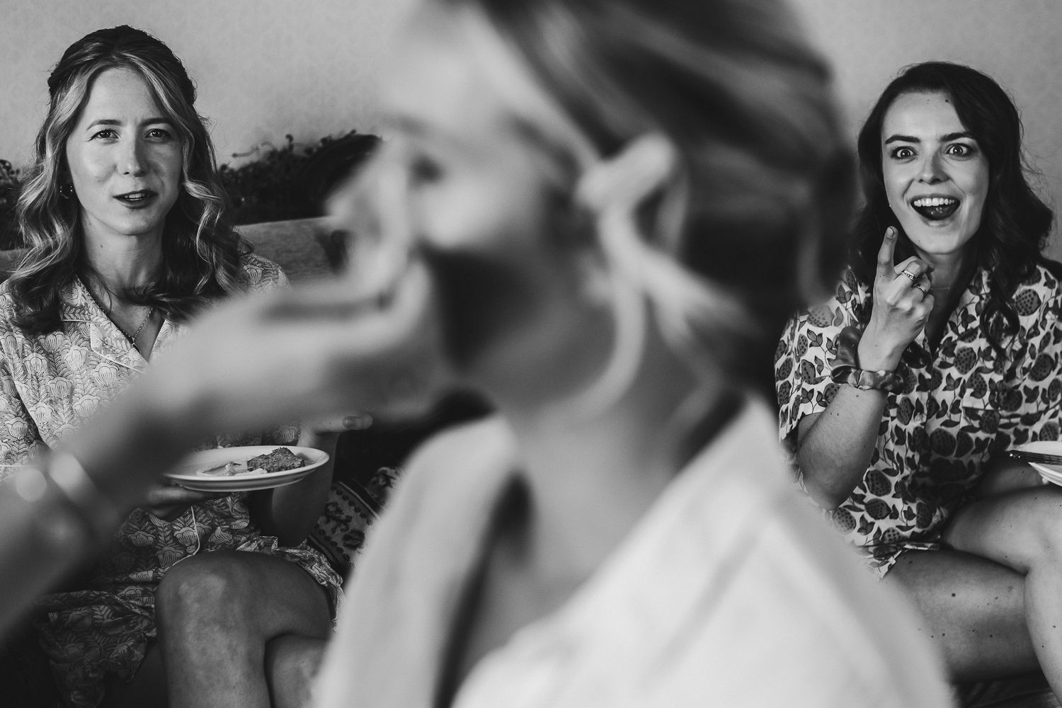 Candid black and white photo of wedding guests laughing together.