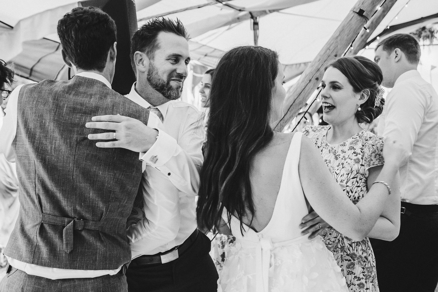 Wedding guests share joyful conversations during an outdoor reception celebration.