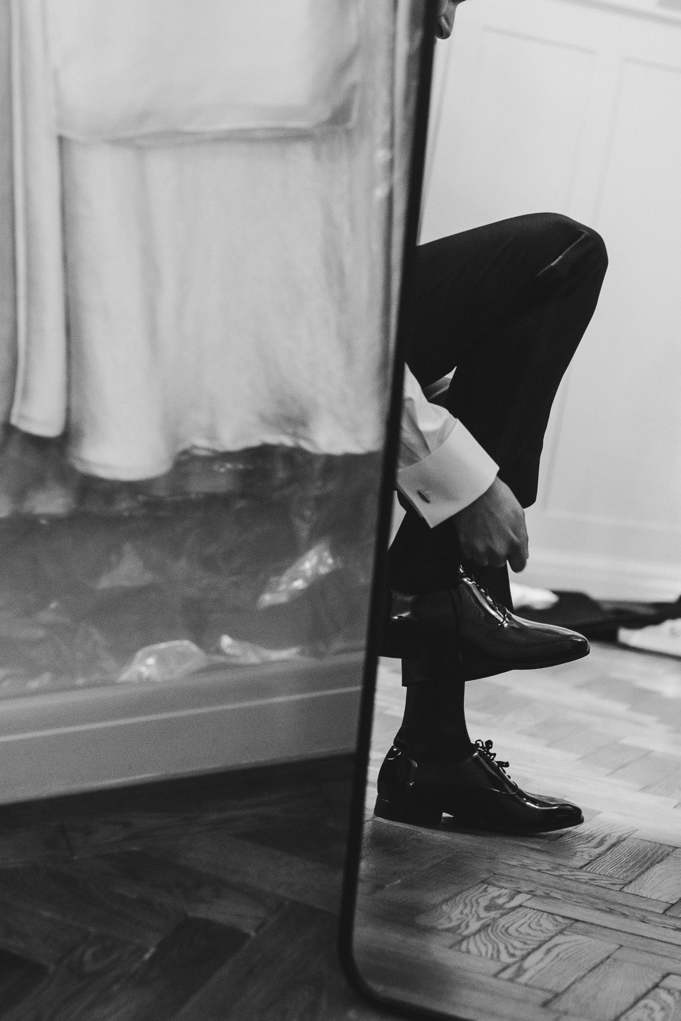 A sequence of black and white photos showing dress shoes walking across a wooden floor.
