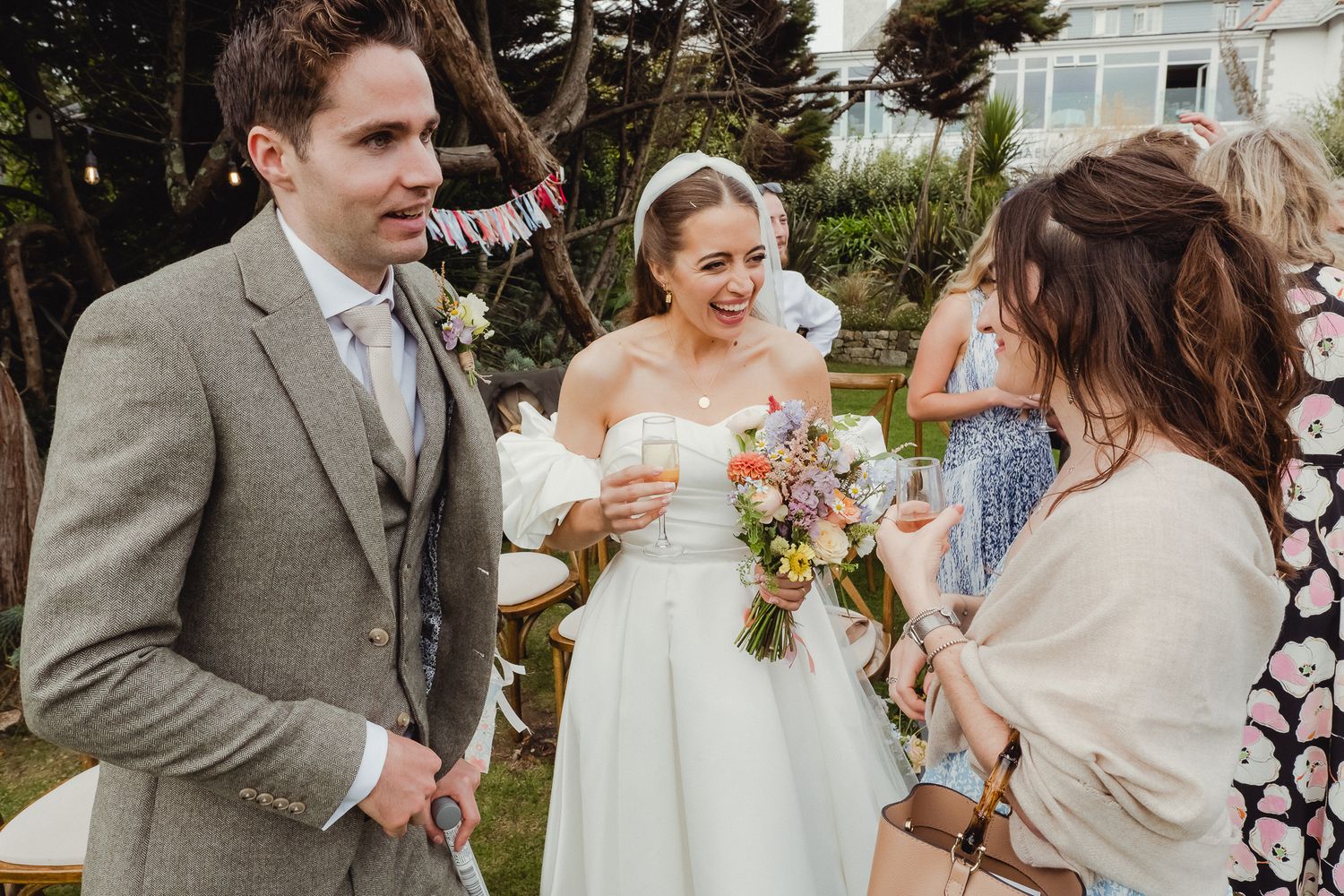 Wedding party laughs and celebrates together outdoors in a candid moment during a spring celebration.