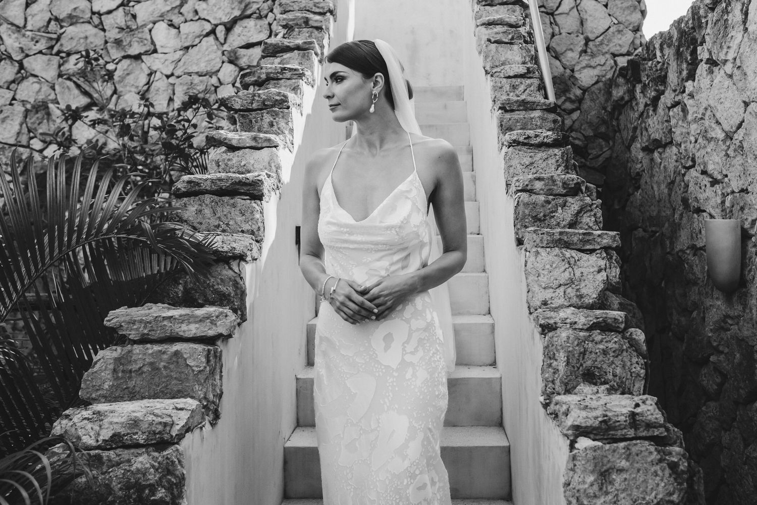 A series of black and white bridal portraits against a rustic stone wall backdrop at an outdoor venue.