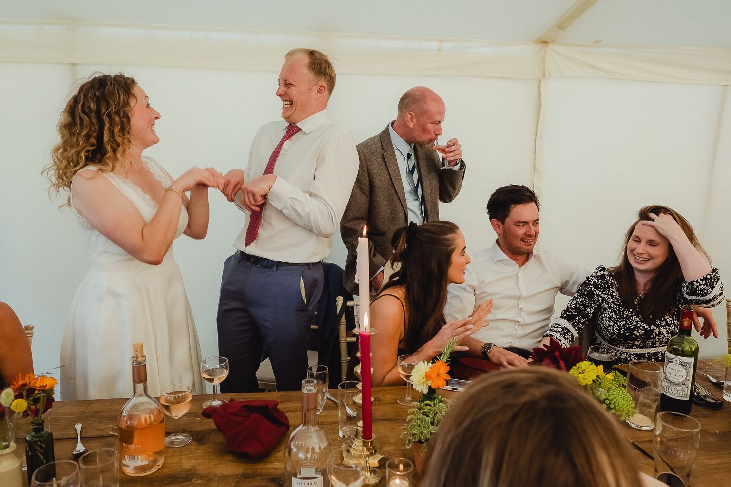 A group of people enjoying food and drinks while socializing at a casual gathering in a tent setting.