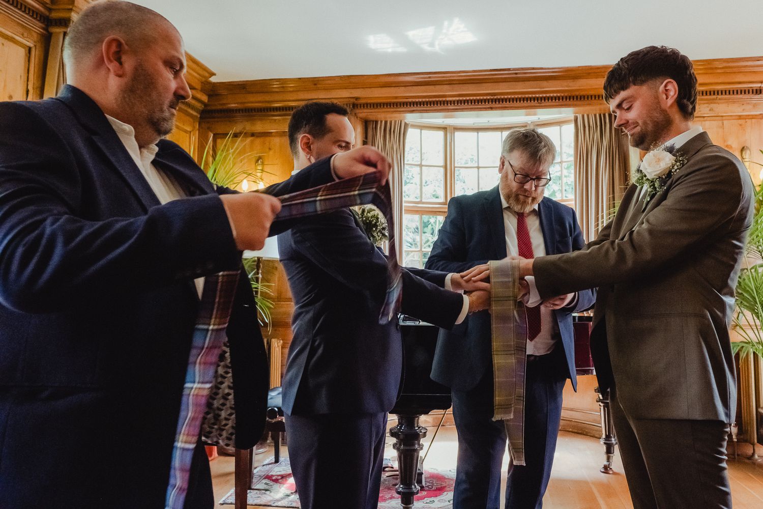 A group of people in business attire gather in a wood-paneled room examining documents together.
