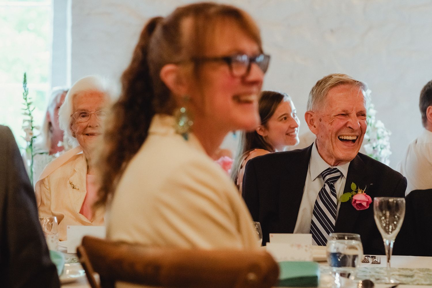 Wedding guests laughing together at a reception table as they enjoy a joyous celebration.