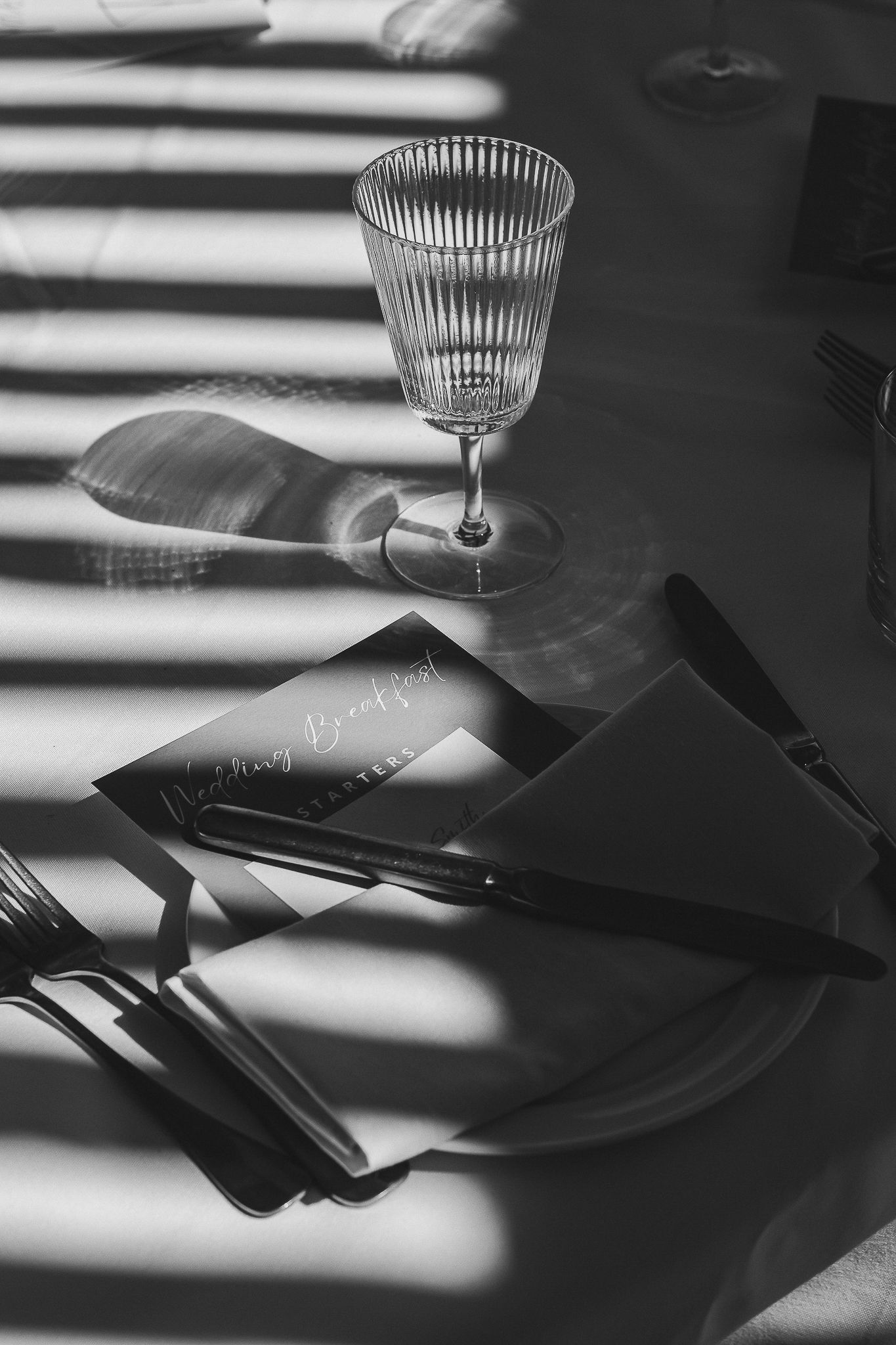 Black and white photo series shows dramatic shadows and light on papers with a glass creating abstract patterns.