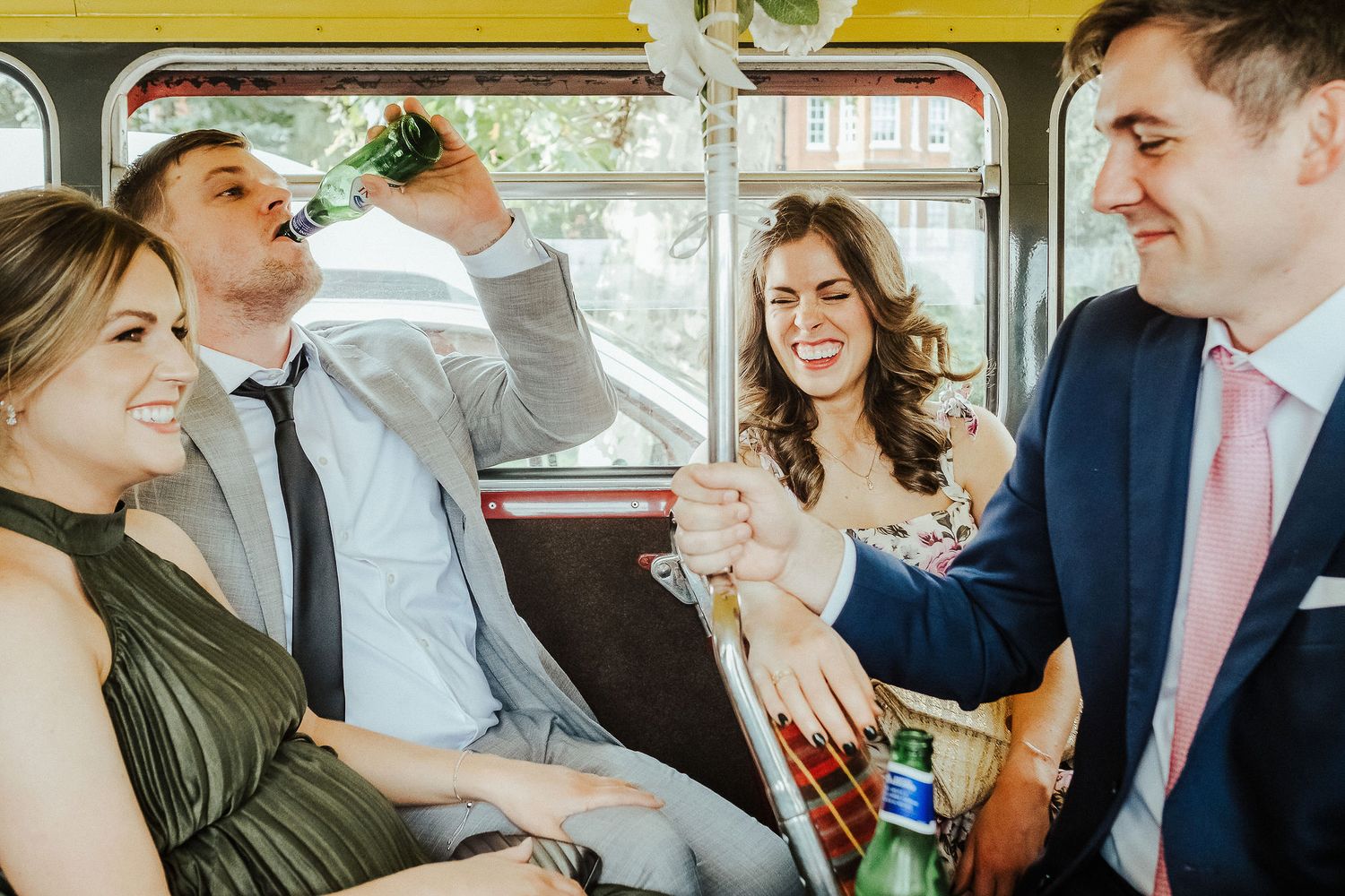 Group of people laughing and celebrating together while riding in a vintage bus or trolley.