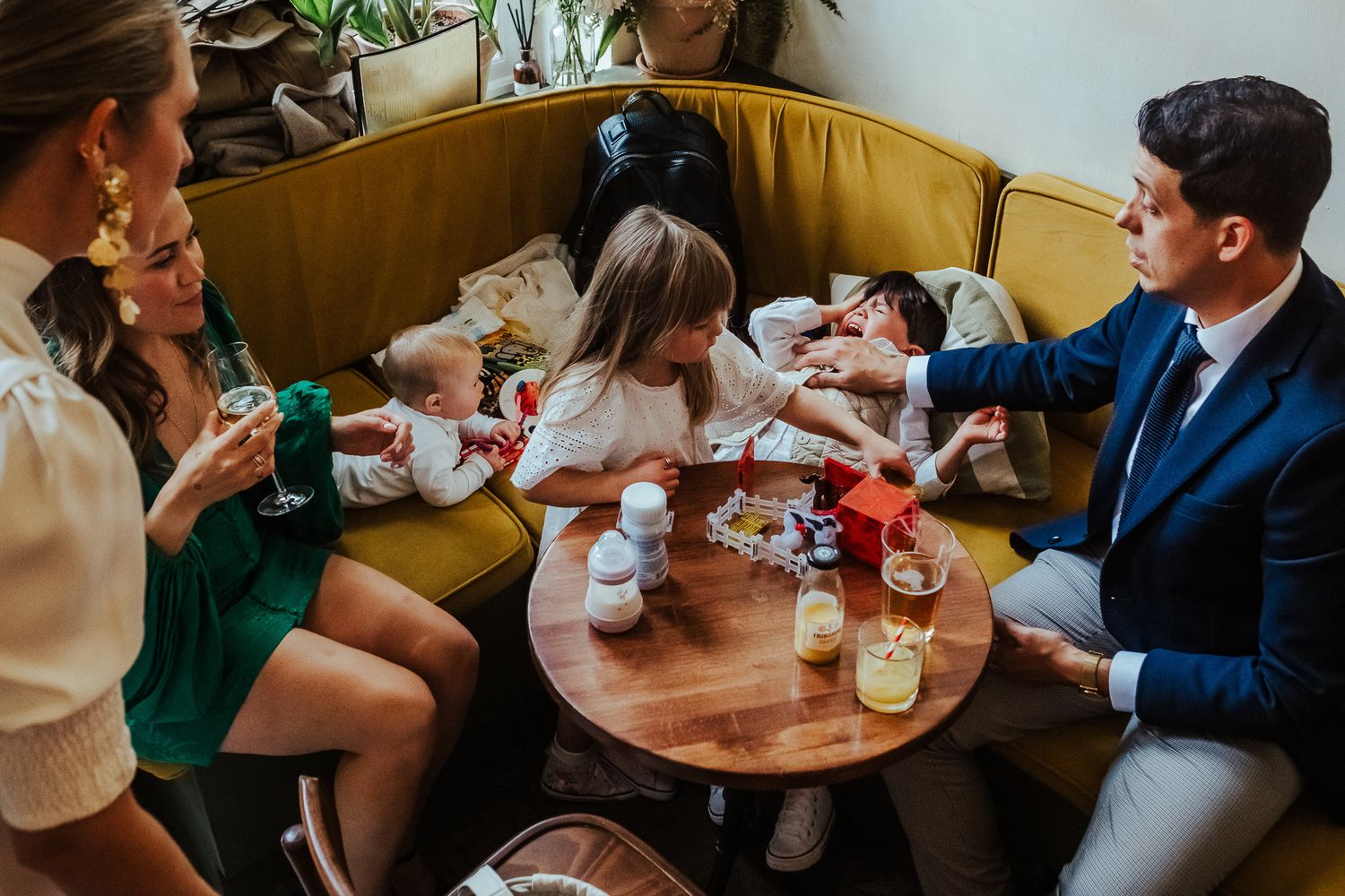 Group enjoying beverages and conversation while gathered around a wooden table at a cozy cafe booth.