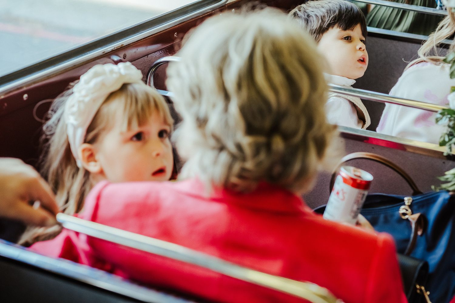 Children seated in the backseat of a car looking towards the side window during a journey.