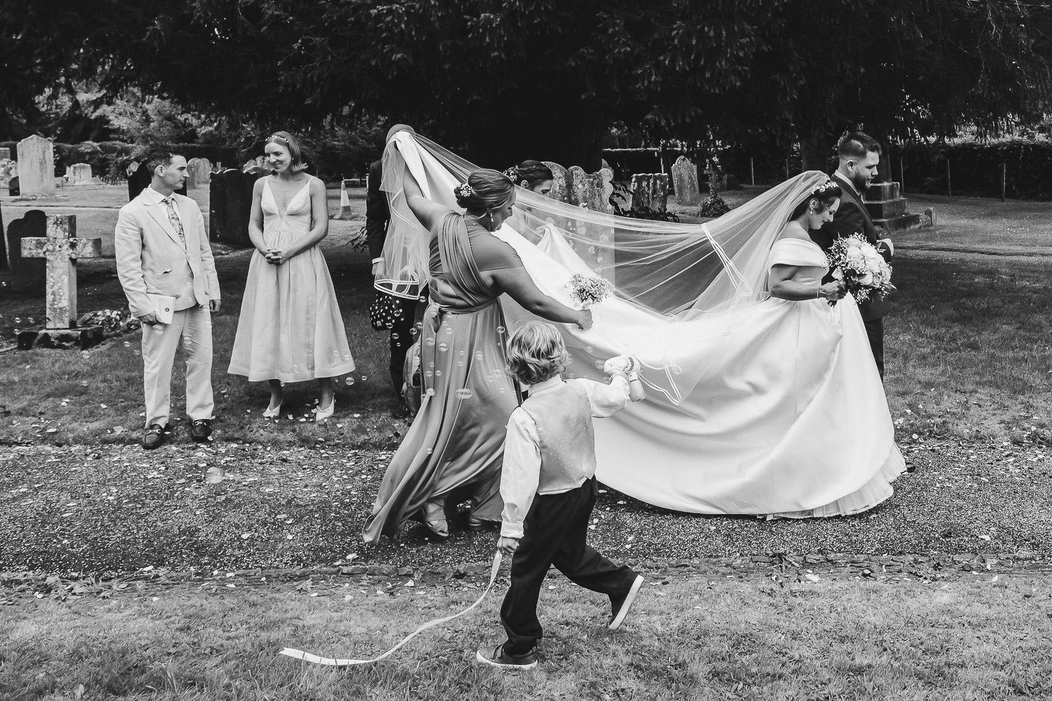 A series of black and white photos showing children playing with a large flowing white fabric outdoors in a park setting.