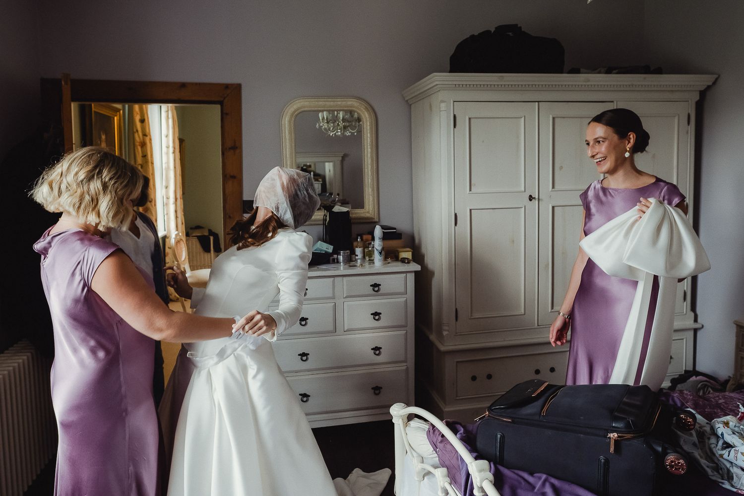 A series of wedding preparation moments showing a light purple bridesmaid dress and white wedding gown in a classic room.