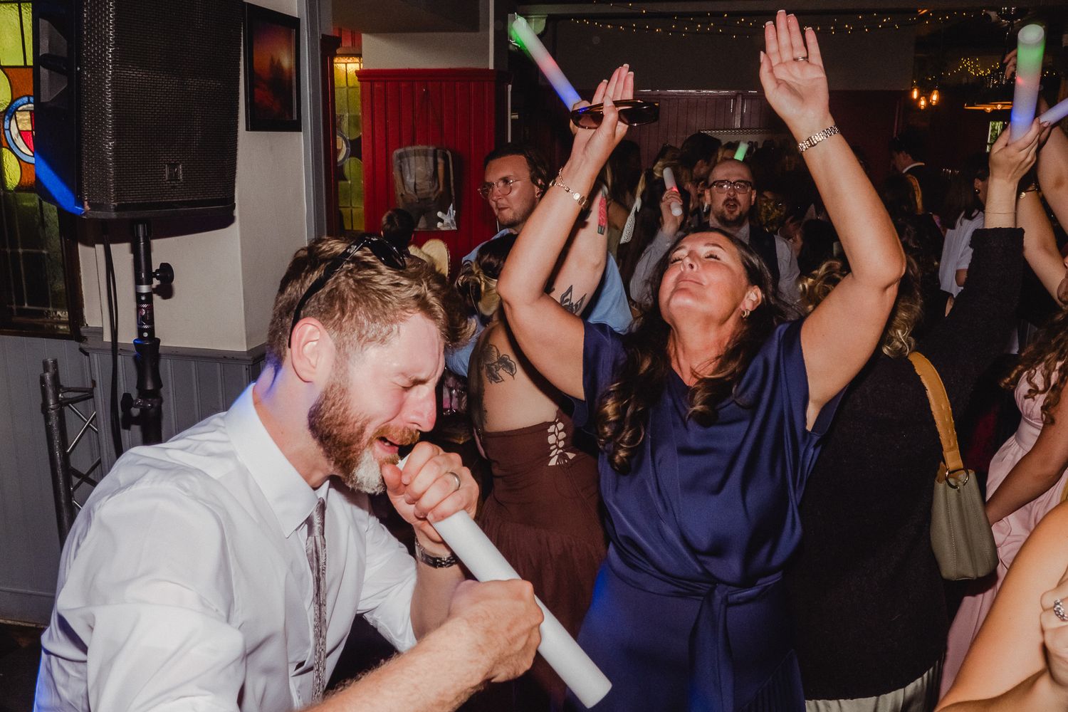 People dancing and celebrating at a lively wedding reception party on a dance floor.