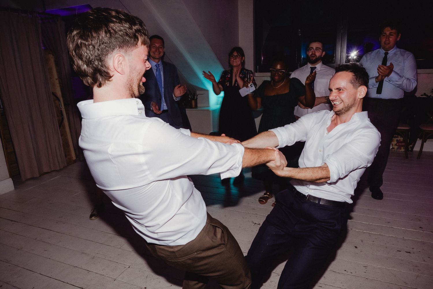 Wedding guests dancing and having fun on a dance floor at a reception celebration.
