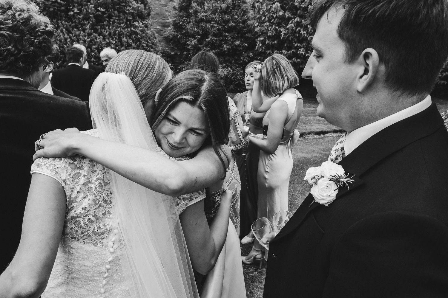 Wedding guests share loving embraces during an emotional wedding reception celebration.