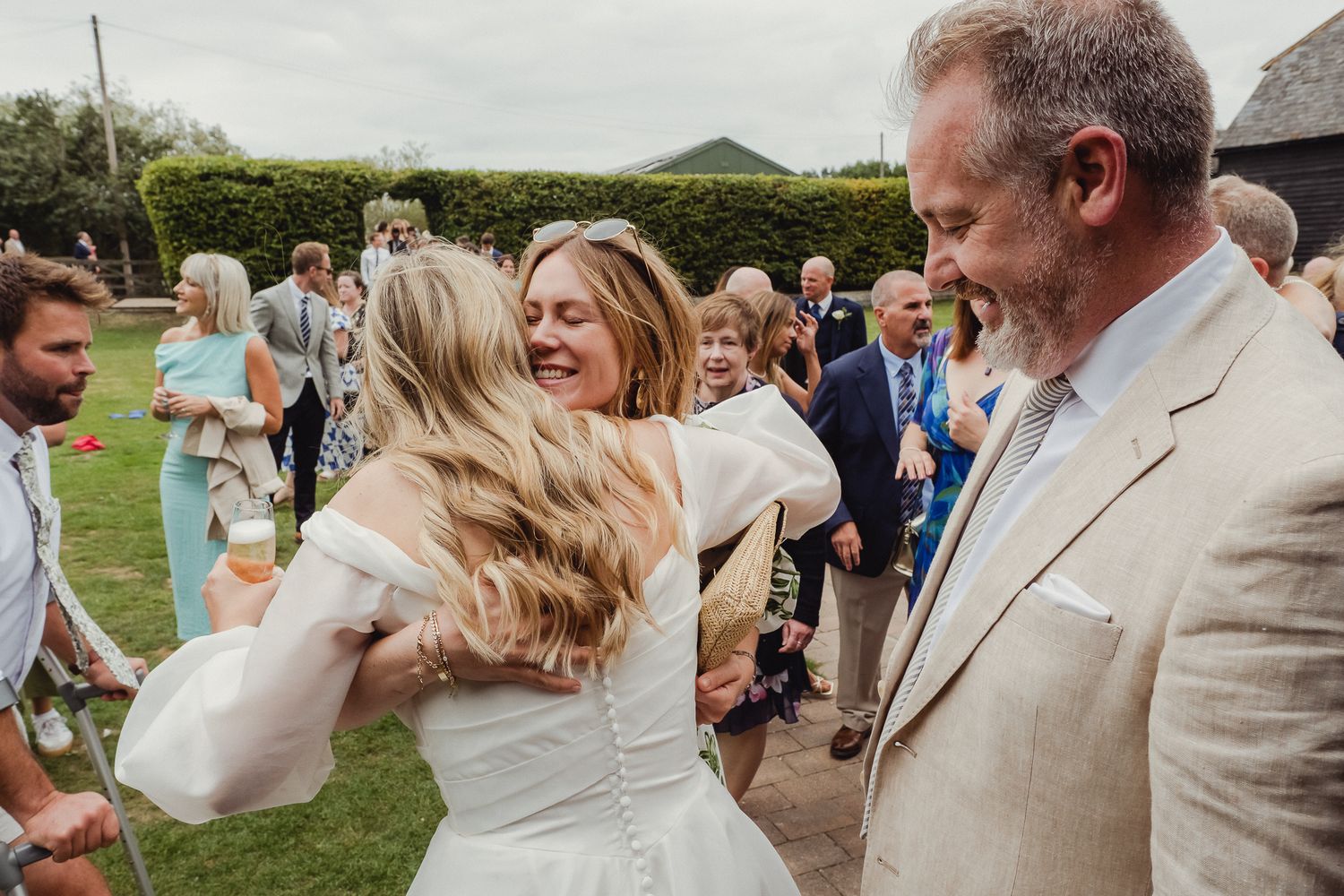 Wedding guests celebrate and dance together during an outdoor reception at a scenic countryside venue.