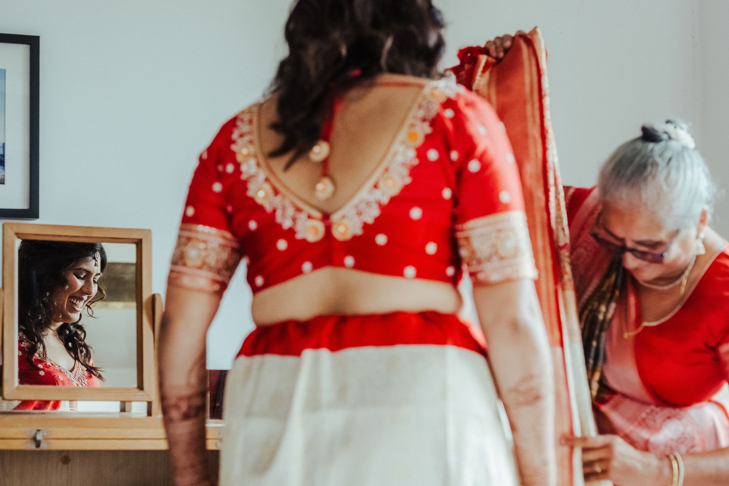 Women in red traditional outfits during preparation moments.