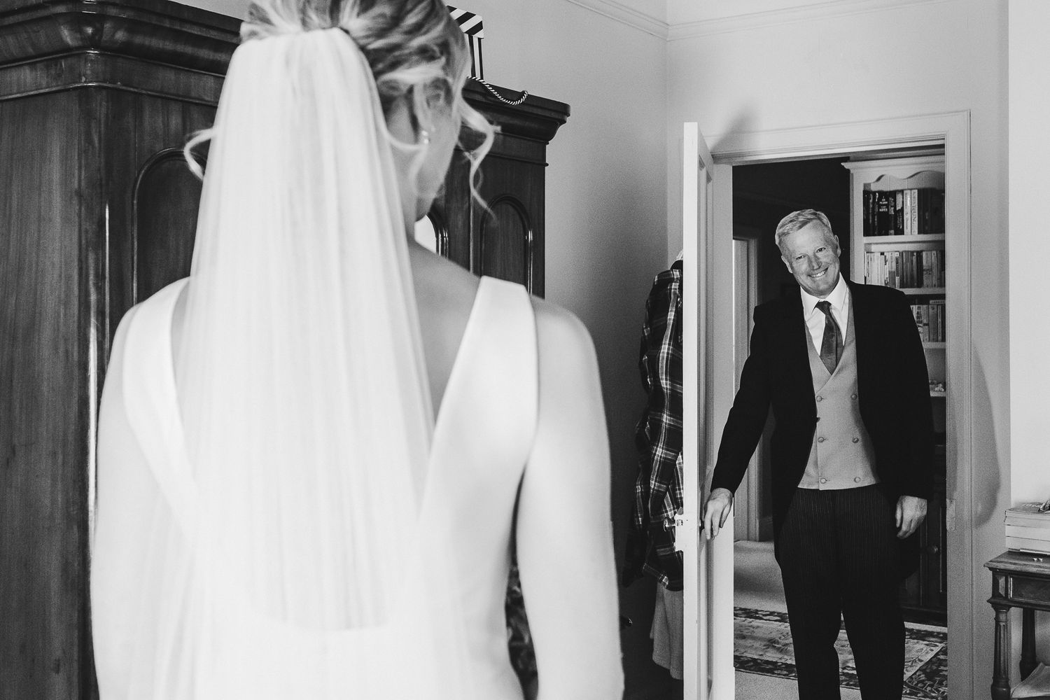 Black and white photo of a father's first look at his daughter in her wedding dress.
