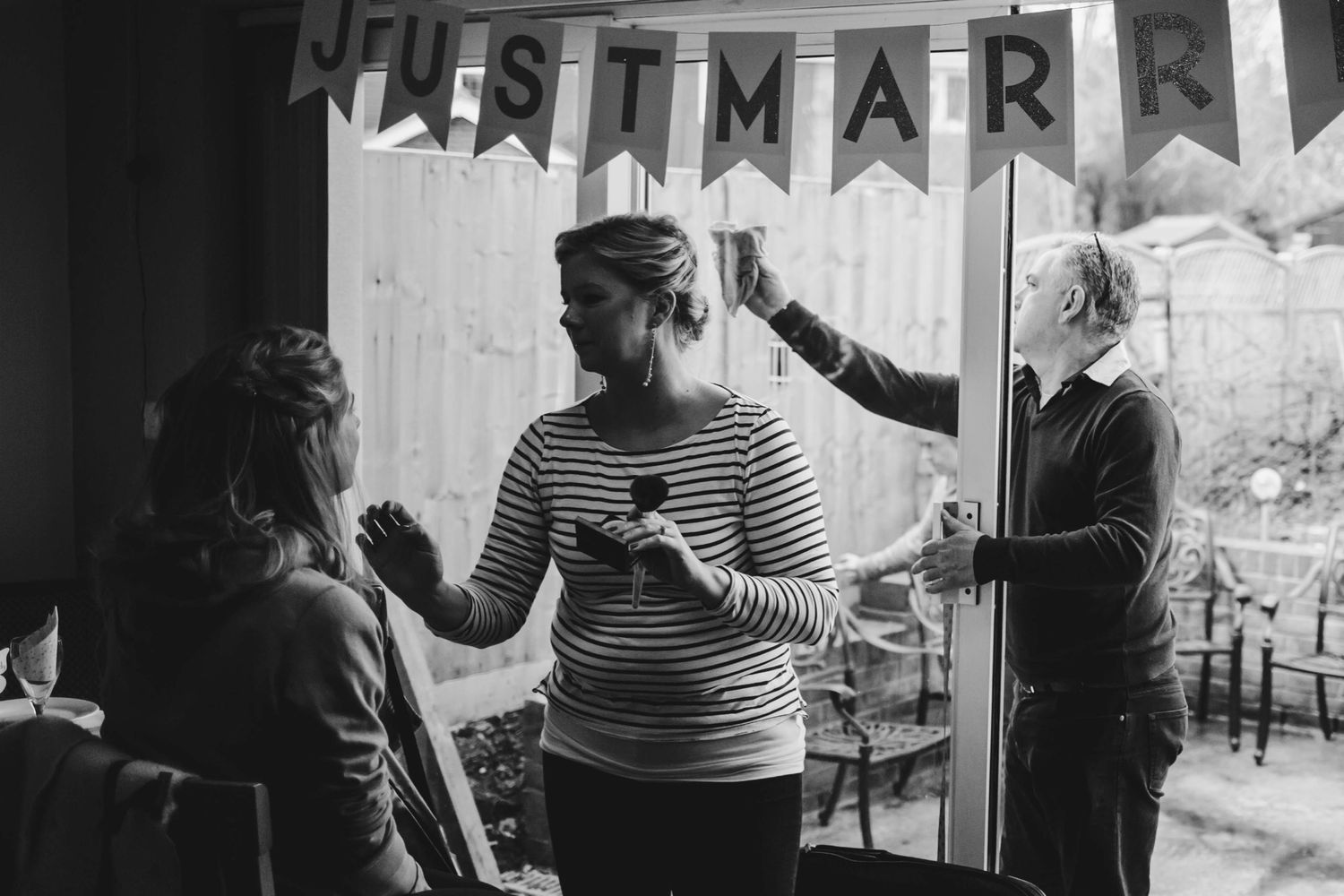 People setting up wedding decorations with Just Married banner in rustic venue.