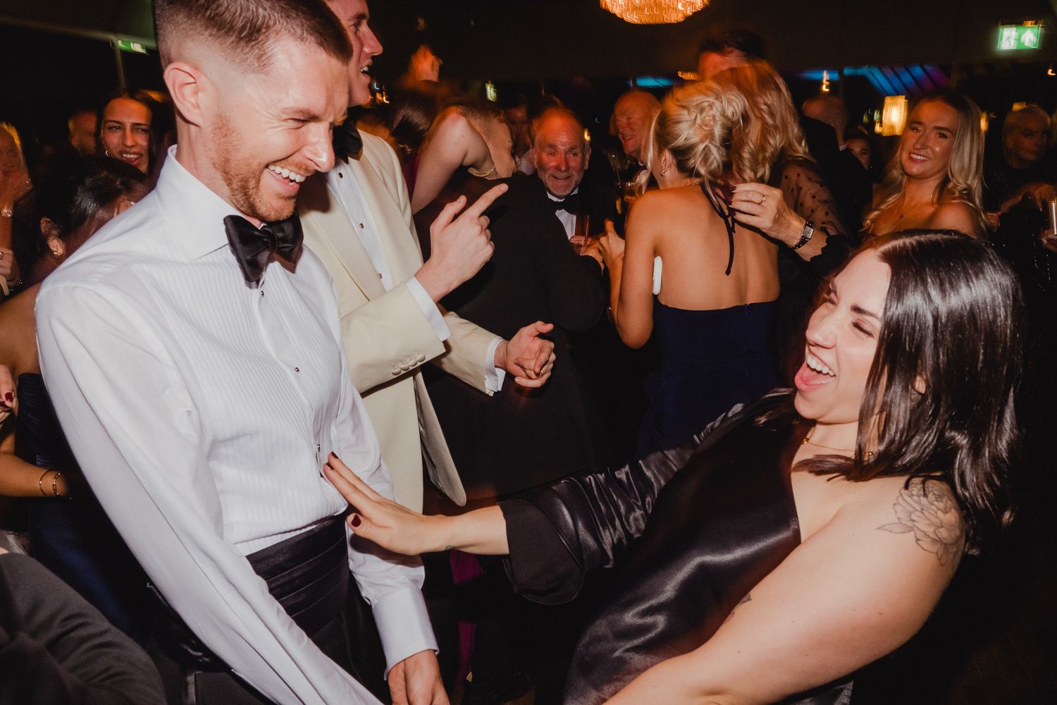 Couples dancing and enjoying themselves at an elegant evening wedding reception with ambient lighting.